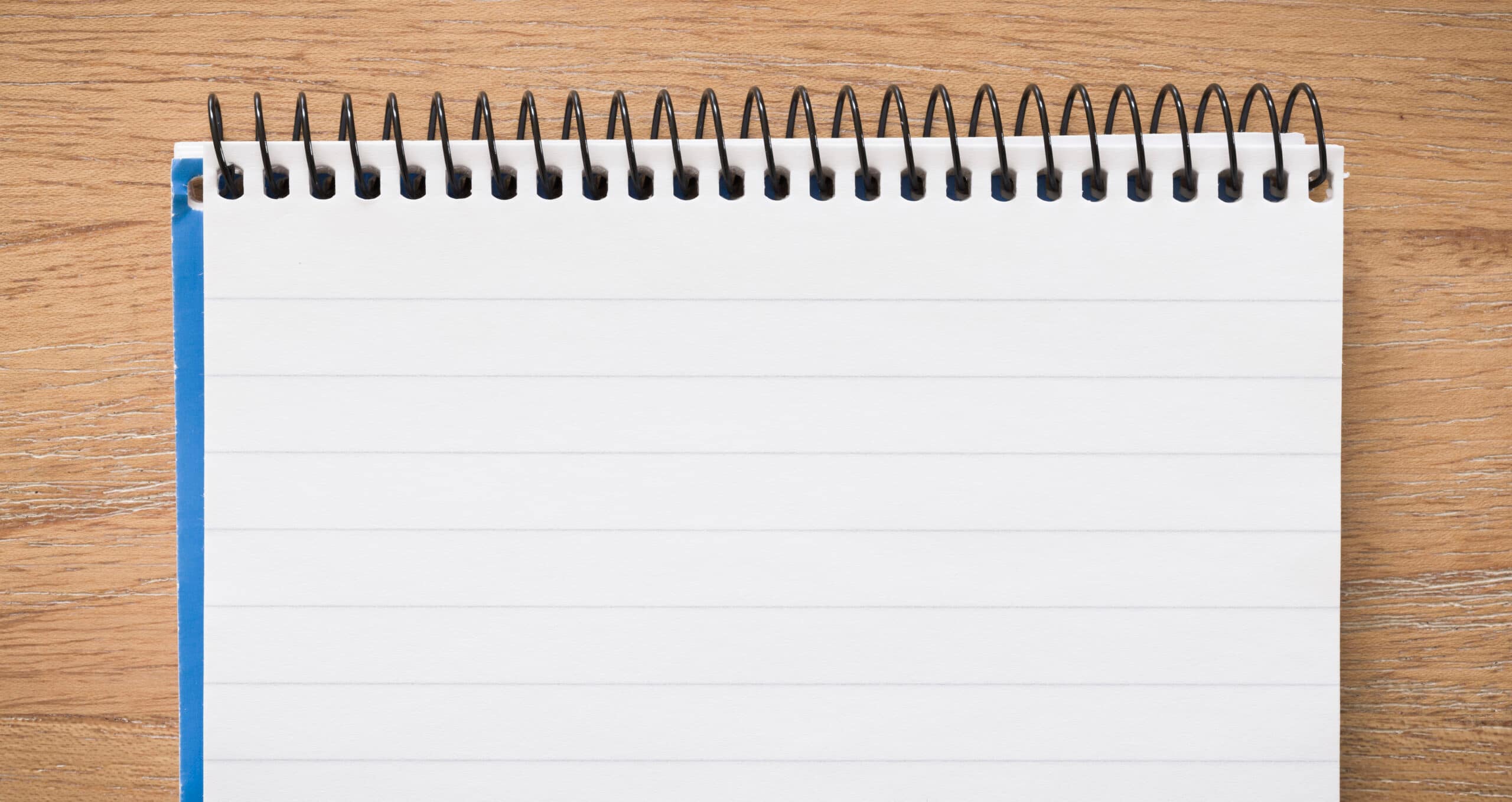 Top of spiral bound notebook open on a wooden desk, flat lay ideal for background or template